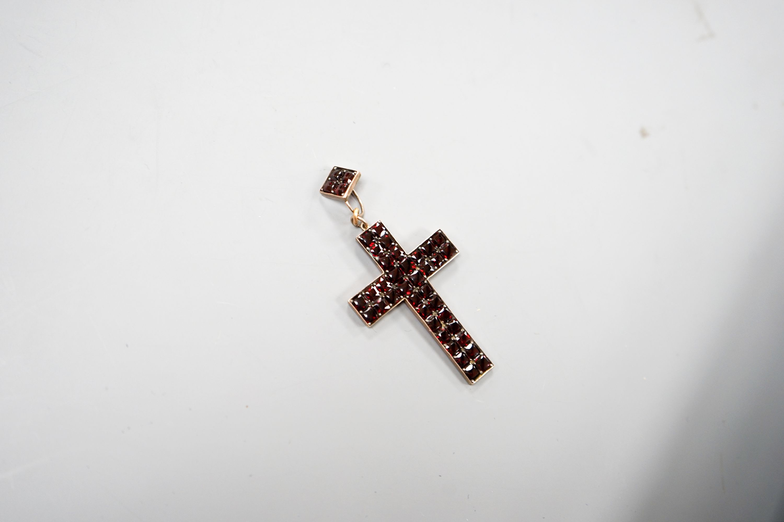 A yellow metal and pave set garnet cross pendant, overall 69mm, gross weight 6.7 grams.